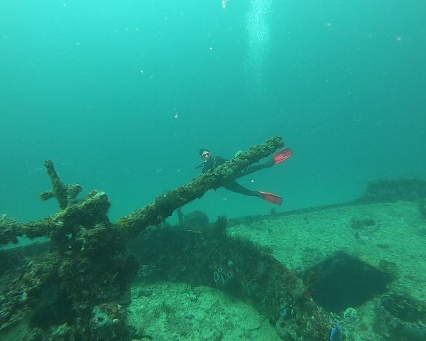 Diver on the deck behind the canon of the C-56 Wreck showing the size of the C-56 Wreck in Puerto Morelos