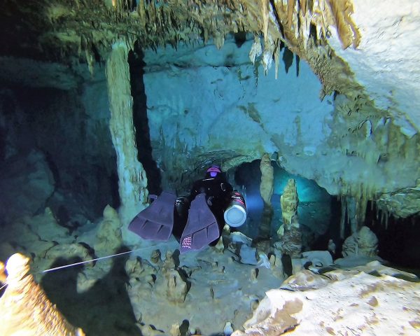 Diver passing through narrow passage in Cenote Taak Bi Ha